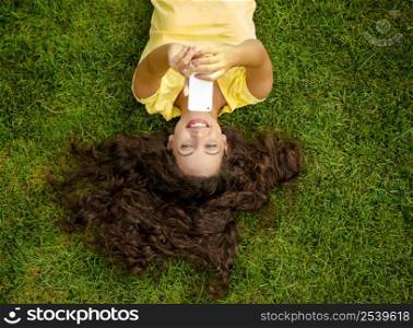 Smiling young woman lying on the grass and making a selfie