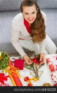 Smiling young woman making Christmas decorations
