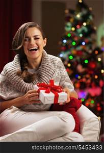 Smiling young woman near christmas tree with present box