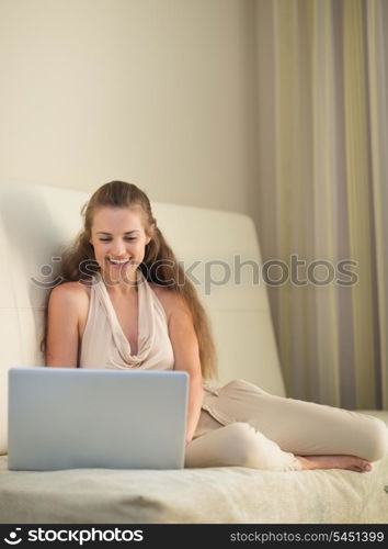 Smiling young woman on couch with laptop
