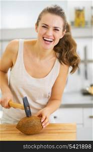 Smiling young woman opening coconut using hammer