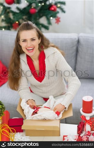 Smiling young woman packing parcel with Christmas gift