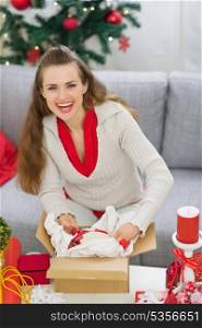 Smiling young woman packing parcel with Christmas gift