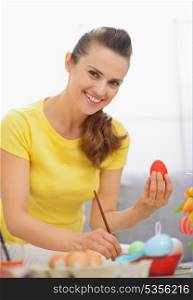 Smiling young woman preparing Easter red eggs