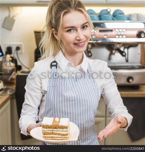 smiling young woman presenting cake slice coffee shop