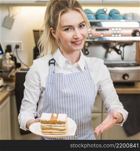 smiling young woman presenting cake slice coffee shop