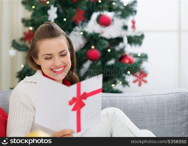 Smiling young woman reading Christmas postcard