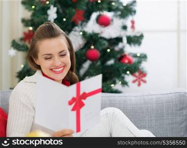 Smiling young woman reading Christmas postcard