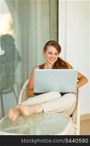 Smiling young woman relaxing on terrace with laptop