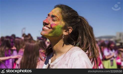 smiling young woman s face painted with holi color