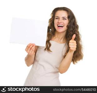 Smiling young woman showing blank paper and thumbs up