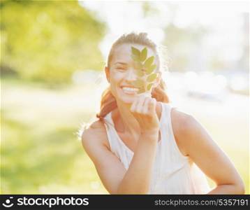 Smiling young woman showing branch with leaves