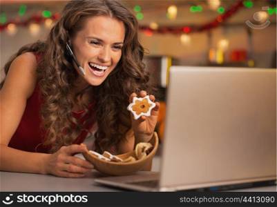 Smiling young woman showing christmas cookies while having video chat on laptop