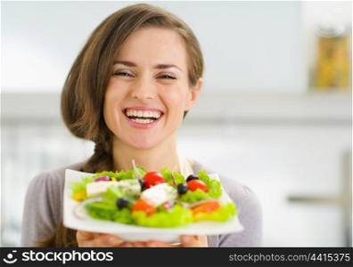 Smiling young woman showing fresh salad