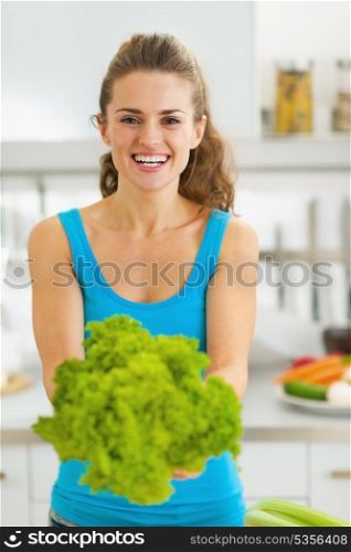 Smiling young woman showing fresh salad