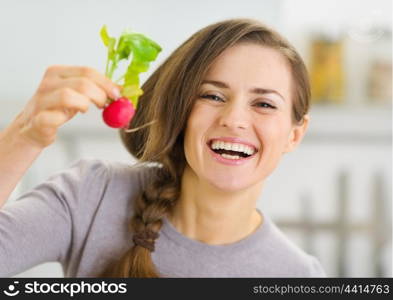 Smiling young woman showing radish