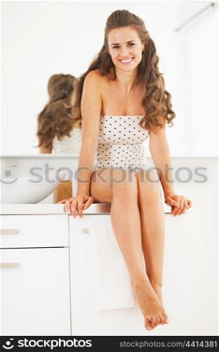 Smiling young woman sitting in bathroom