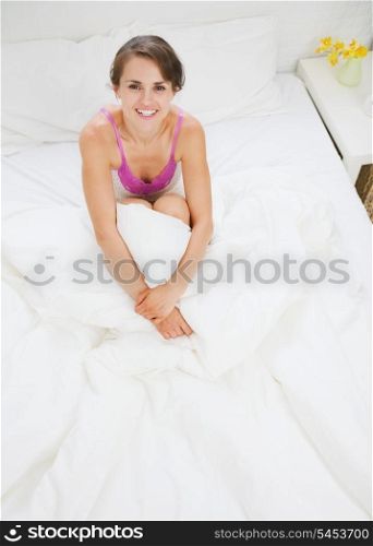Smiling young woman sitting on bed