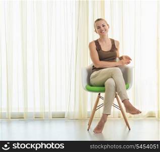 Smiling young woman sitting on modern chair
