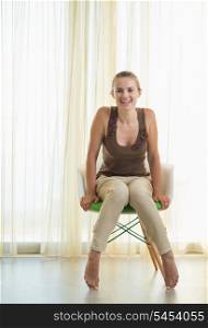 Smiling young woman sitting on modern chair