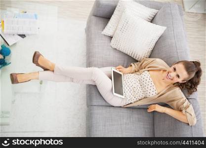 Smiling young woman sitting on sofa with tablet pc
