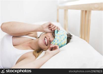smiling young woman sleeping bed with eye mask