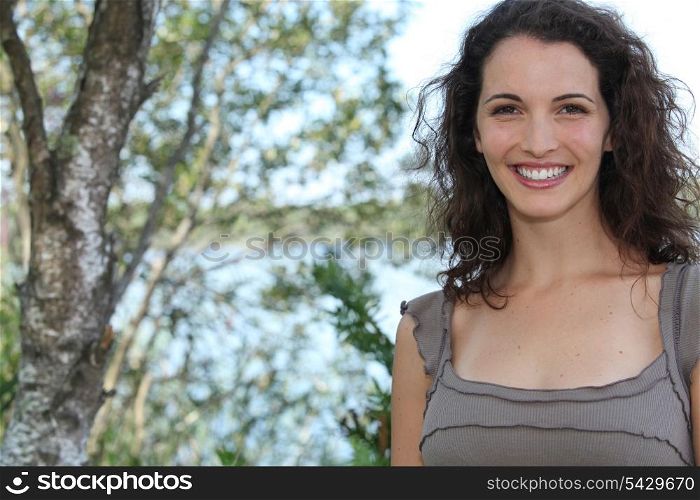 Smiling young woman standing next to a tree
