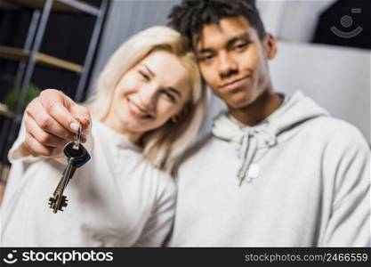 smiling young woman standing with his boyfriend showing house keys toward camera