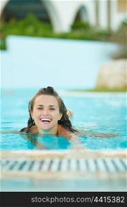 Smiling young woman swimming in pool