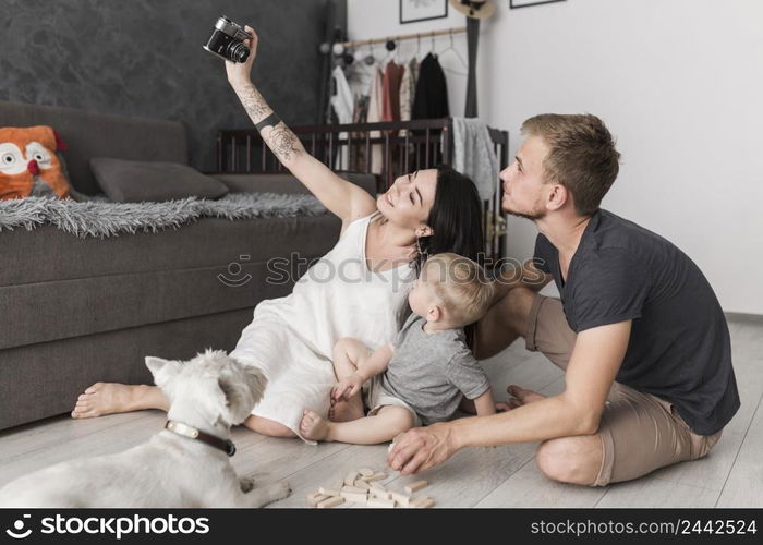 smiling young woman taking selfie her family while sitting living room