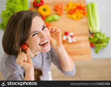 Smiling young woman using cherry tomatos as earring