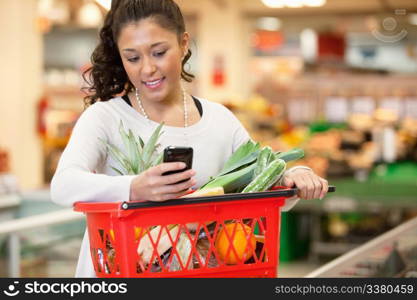 Smiling young woman using mobile phone while shopping in shopping store