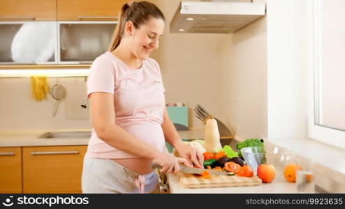 Smiling young woman waiting for baby cooking on kitchen and doing housework. Concept of healthy lifestyle and nutrition during pregnancy.. Smiling young woman waiting for baby cooking on kitchen and doing housework. Concept of healthy lifestyle and nutrition during pregnancy