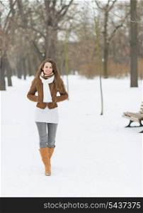 Smiling young woman walking in winter park