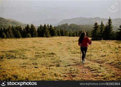 Smiling young woman walking with backpack over green hills