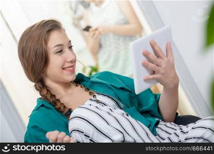 smiling young woman with a braid using a tablet computer