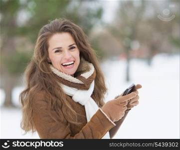 Smiling young woman with cell phone in winter outdoors