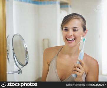 Smiling young woman with electric toothbrush