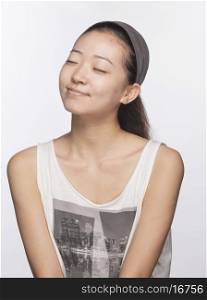 Smiling young woman with eyes closed, studio shot