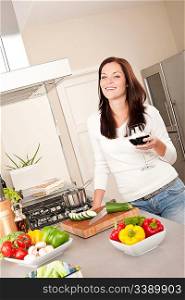 Smiling young woman with glass of red wine in the kitchen