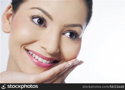 Smiling young woman with hand on chin looking away