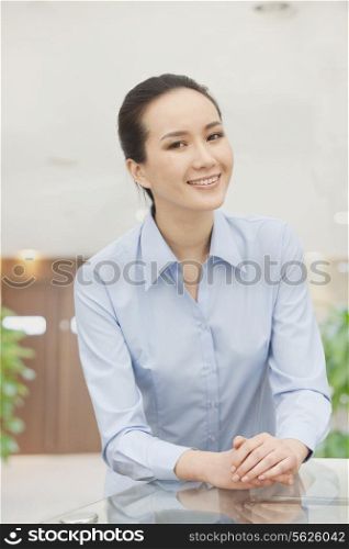 Smiling young woman with hands clasped, portrait
