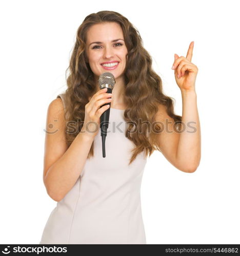 Smiling young woman with microphone pointing up on copy space