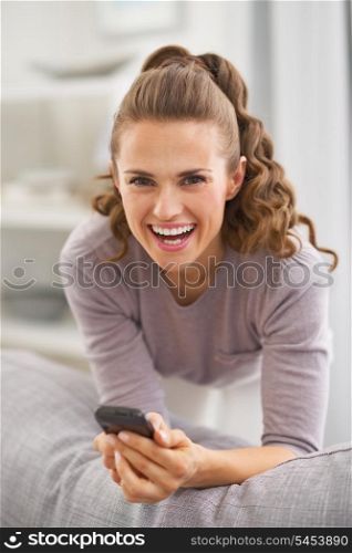 Smiling young woman with mobile phone in living room