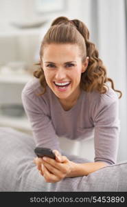 Smiling young woman with mobile phone in living room