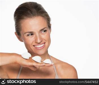 Smiling young woman with seashells looking on copy space