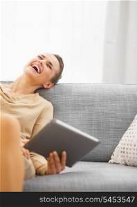 Smiling young woman with tablet pc on couch