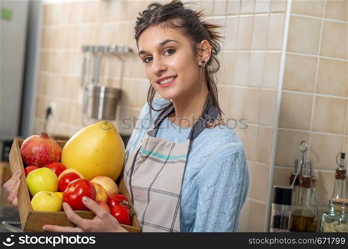 smiling young woman with various fruits in the kitchen