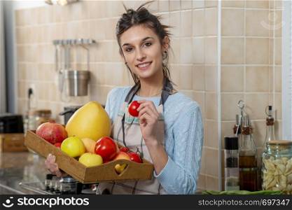 smiling young woman with various fruits in the kitchen