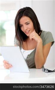 Smiling young woman working on electronic tablet at home